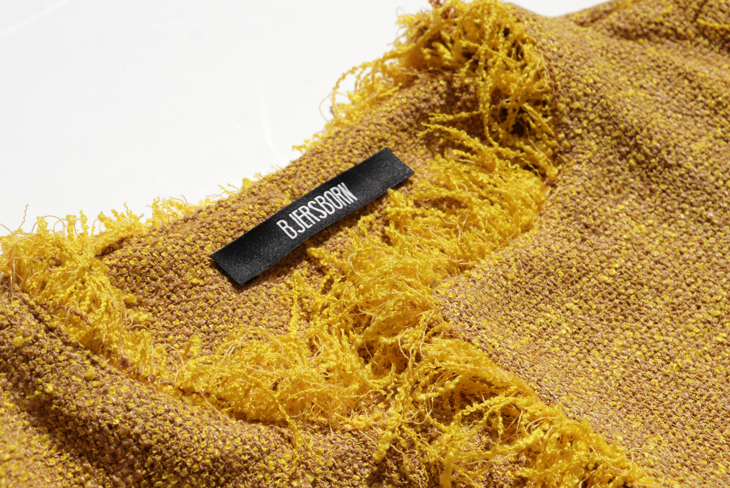 Textured yellow fabric with a brand label on a white background